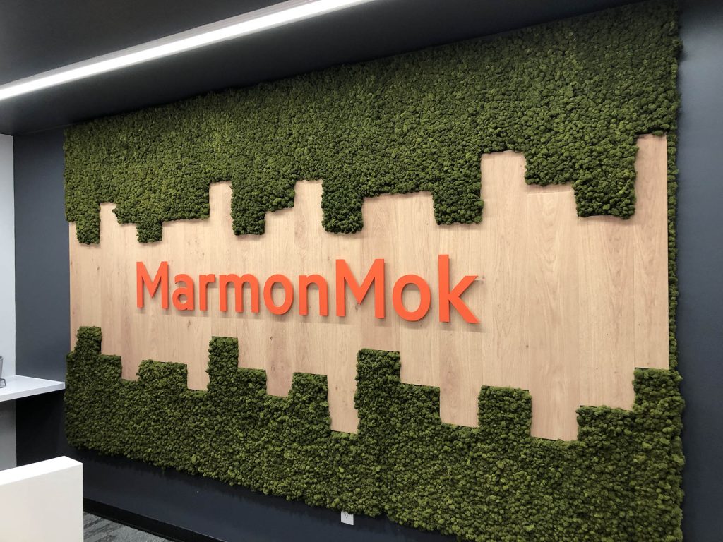 MarmonMok logo on moss-covered wood wall