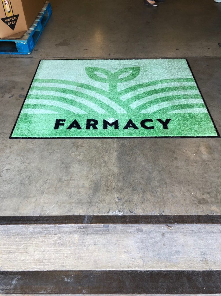 Green 'Farmacy' welcome mat at store entrance.