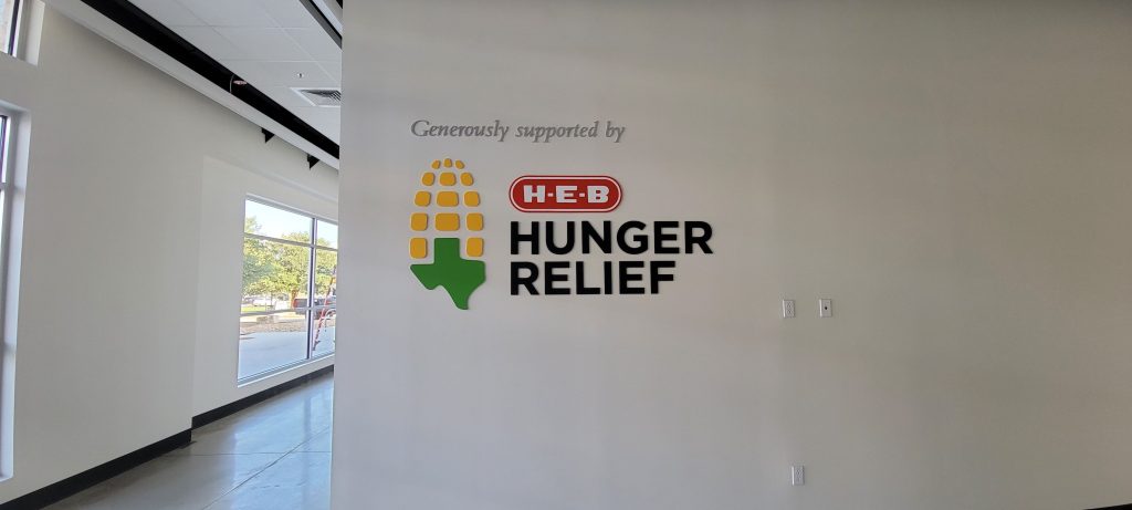 HEB Hunger Relief wall sign with corn graphic.