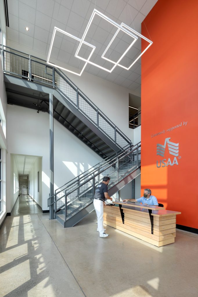 Modern lobby with staircase and bright orange wall.