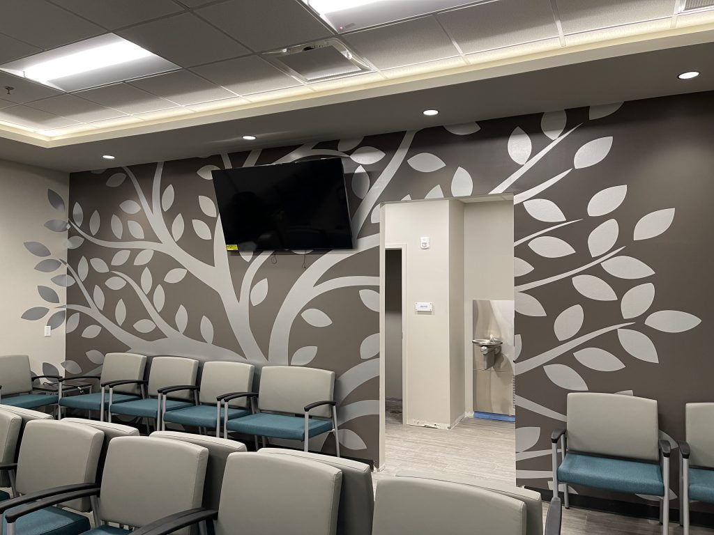 Modern waiting room with tree mural and chairs.