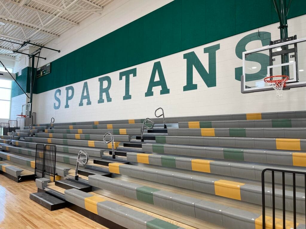 Empty gymnasium bleachers with Spartan mural.